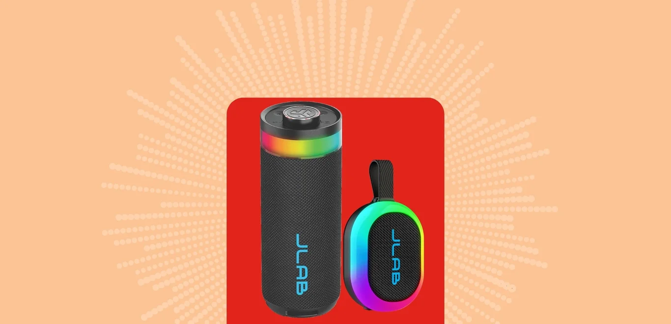 Black Jlab speakers against an orange background covered in yellow fireworks