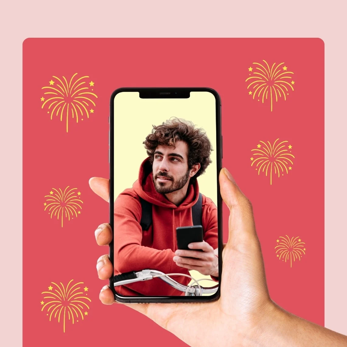 Small gold fireworks burst around a floating hand displaying a phone screen displaying a man on his phone on a medium pink rectangle against a light pink background.